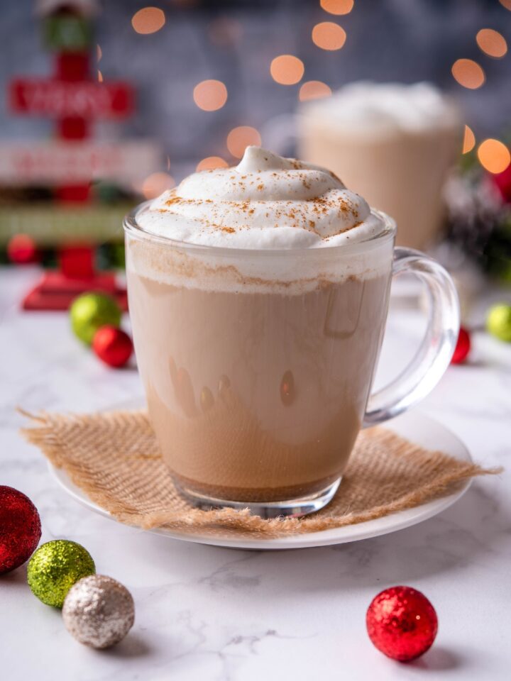Gingerbread latte in clear mug topped with whipped cream.