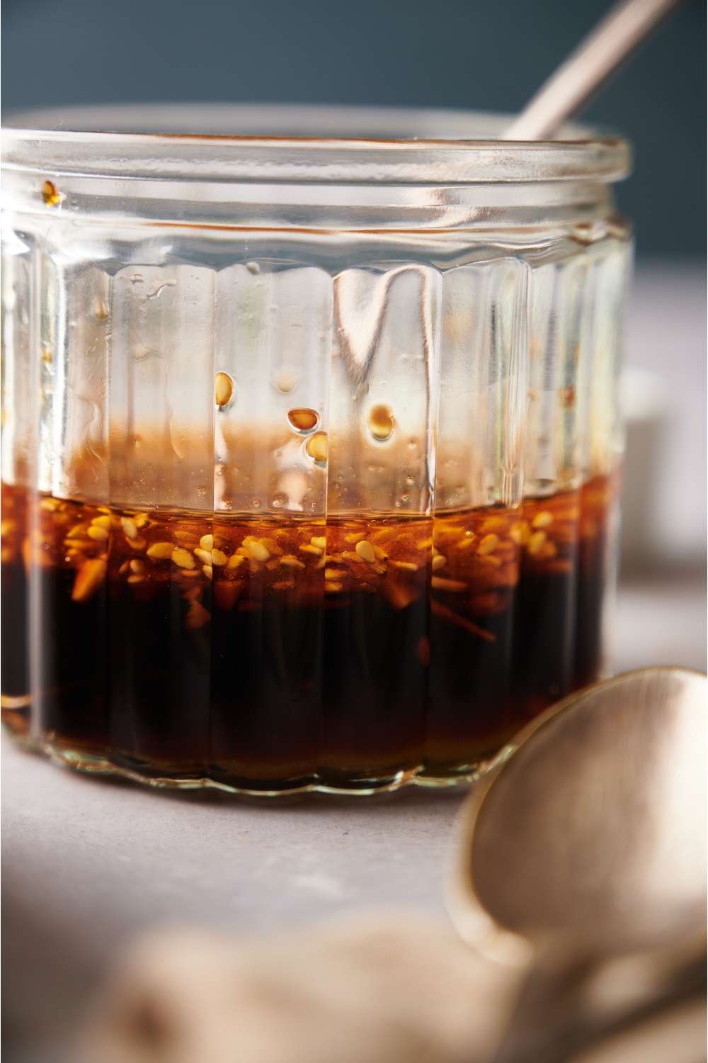 A clear jar containing dumpling sauce and a spoon.