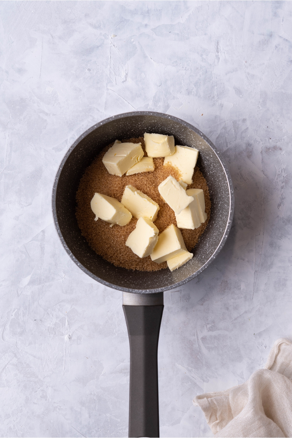 Saucepan filled with brown sugar and cubes of butter.