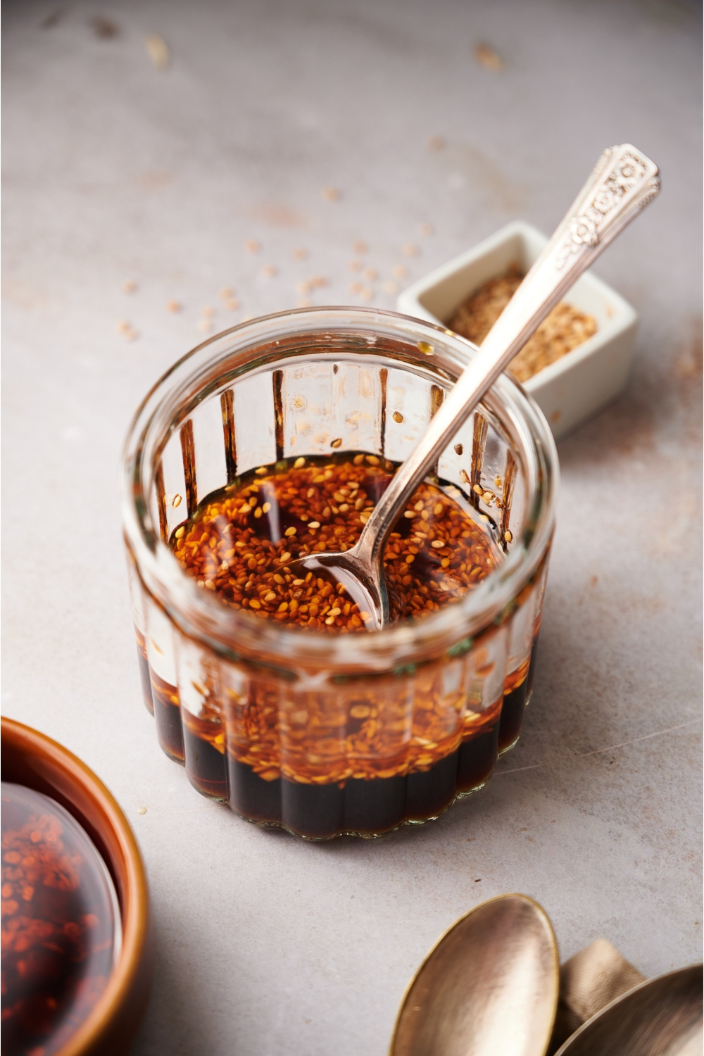 A clear jar containing dumpling sauce and a spoon.