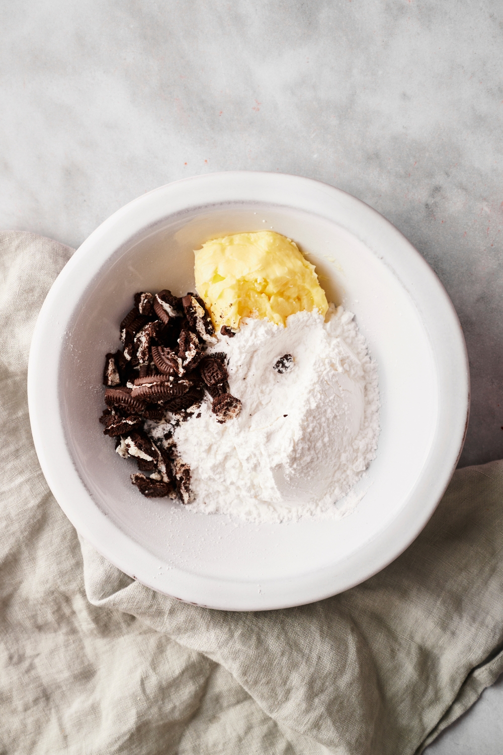 A mixing bowl with flour, oreos, and creamed butter.
