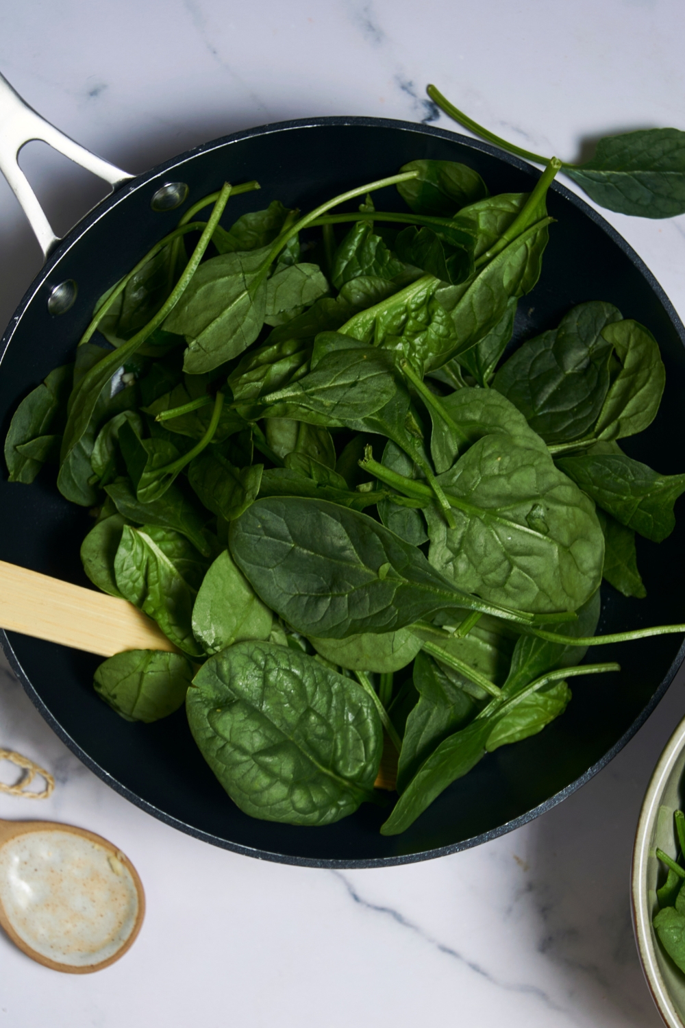 A pan with spinach being cooked down in it.