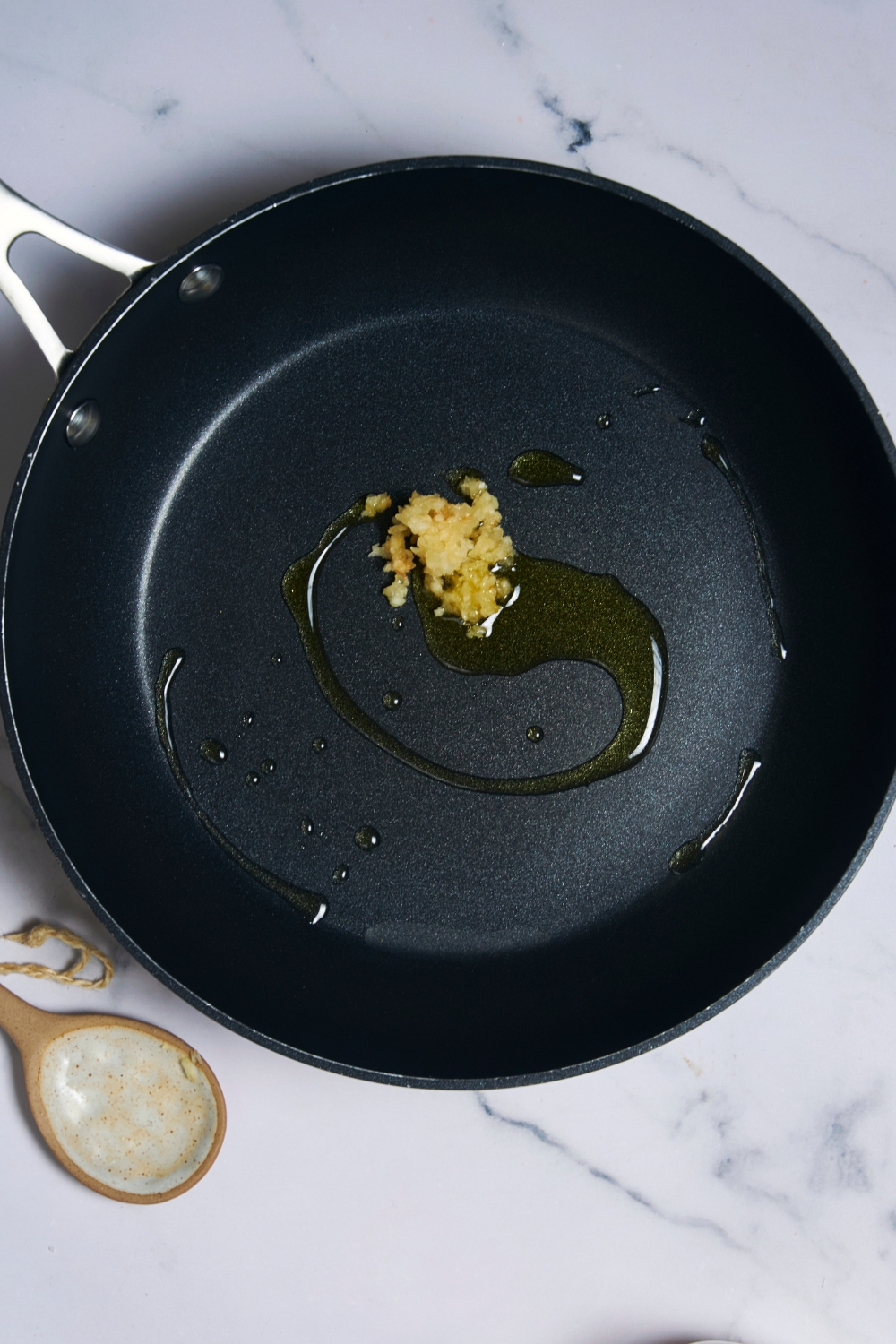 A pan with hot olive oil and mind garlic in it.