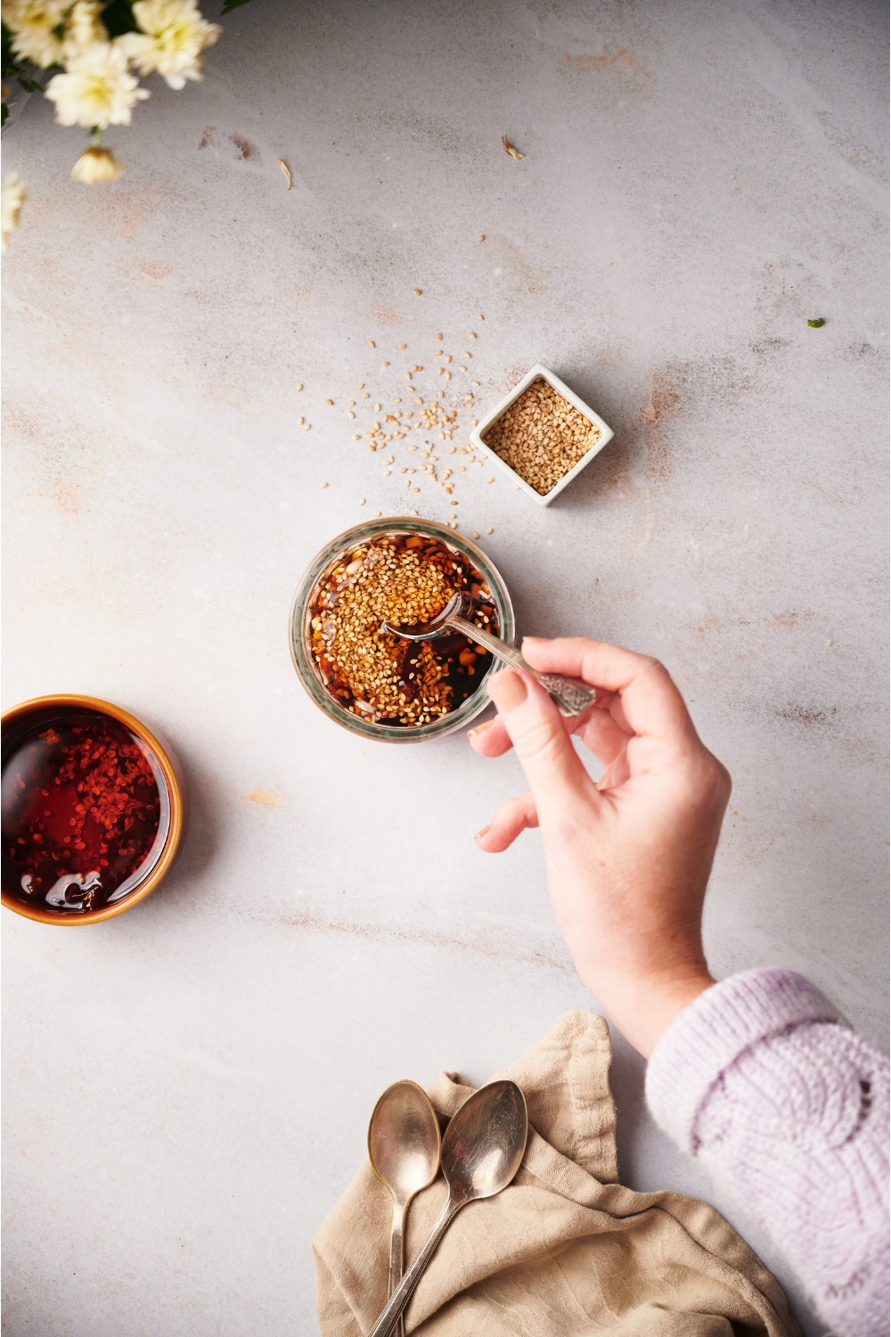 A hand stirring a clear bowl containing dumpling sauce ingredients.