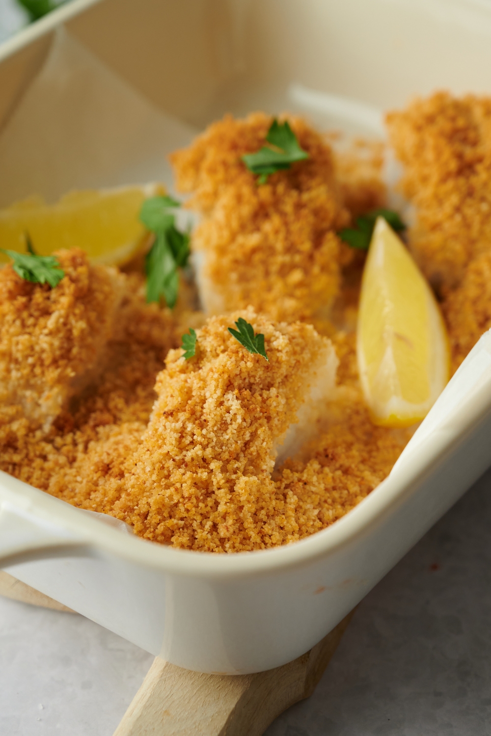 A piece of breaded haddock in a baking dish with more pieces of the breaded haddock.
