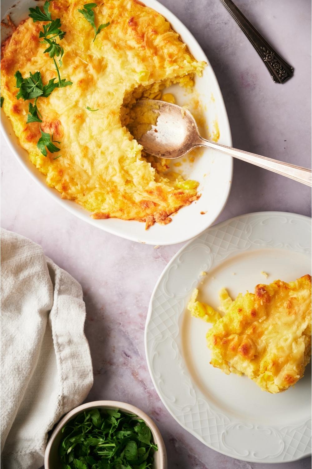 Paula Deen's corn casserole with a serving spoon and a serving of casserole on a second plate