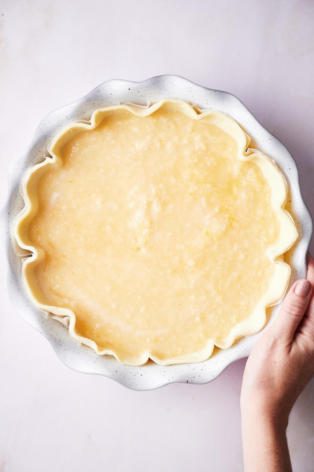 A pie dish with unbaked crust, the pie filling has been poured into it.