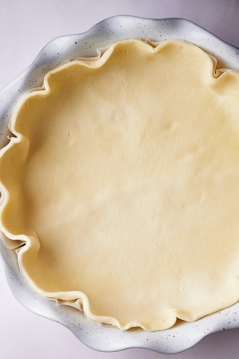 A baking dish with an uncooked pie crust.