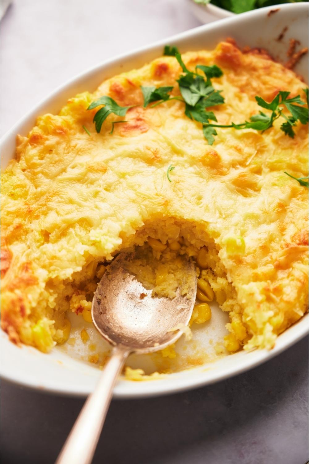 Paula Deen's corn casserole with a serving spoon and a serving removed