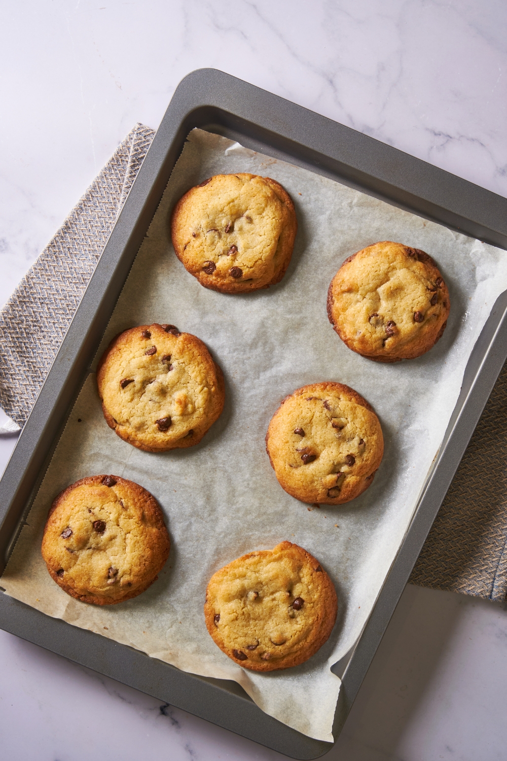 Six baked cookies on top of a baking sheet that is lined with parchment paper.
