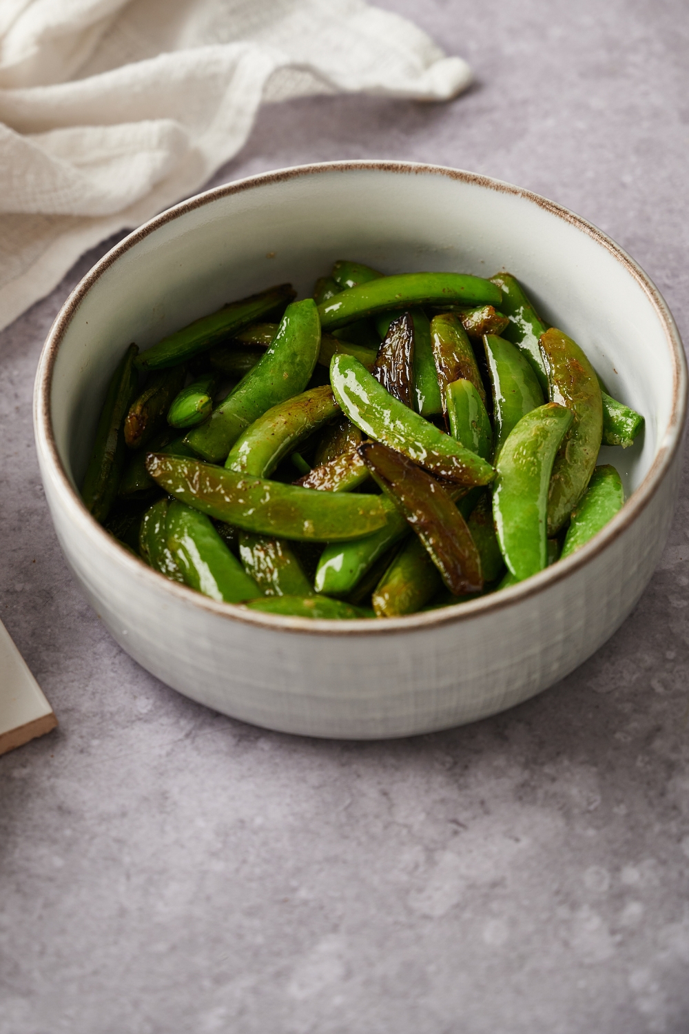 A small bowl with butter snap peas.