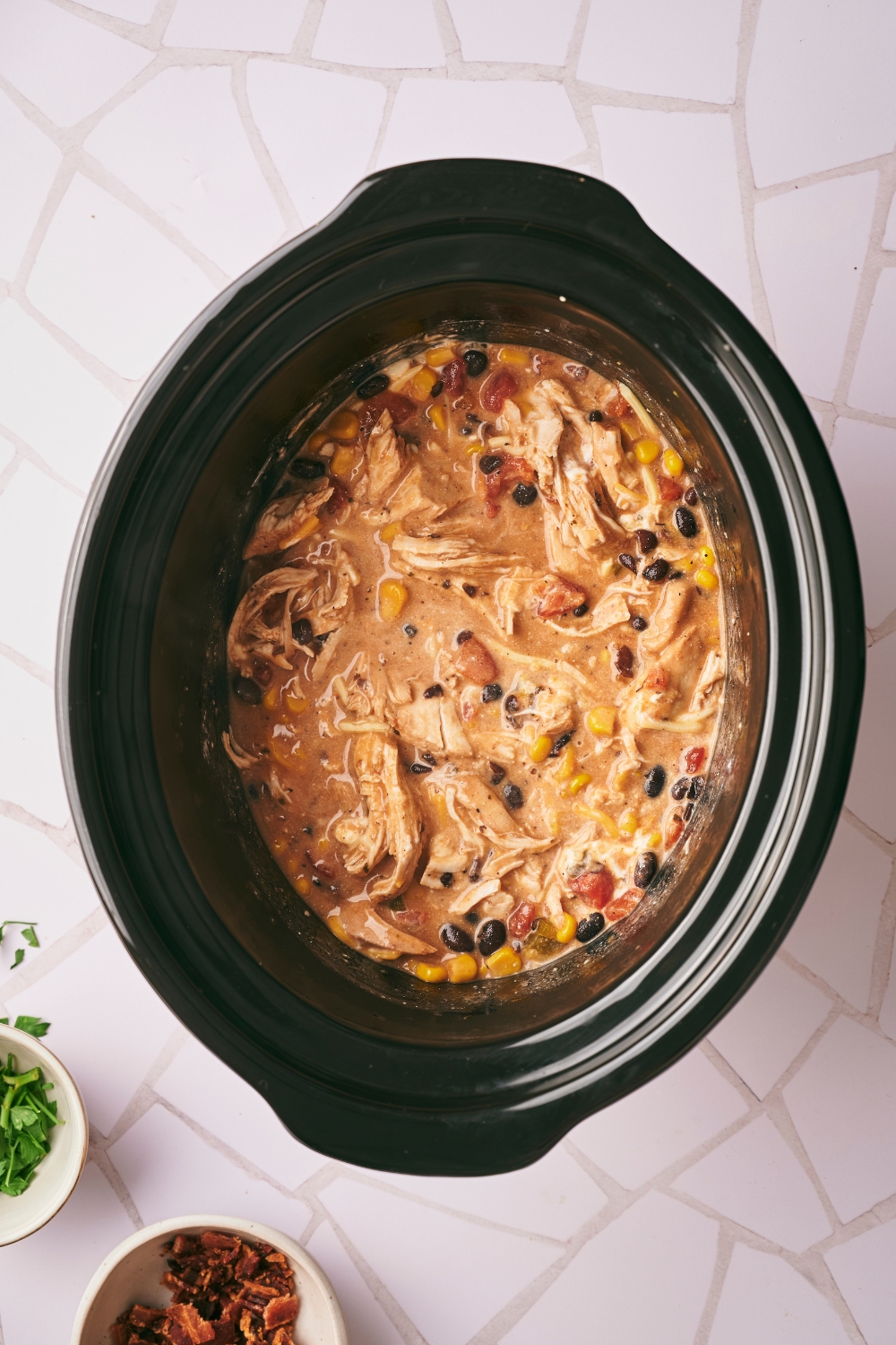 Shredded chicken, black beans, and corn in a creamy sauce in a crock pot.