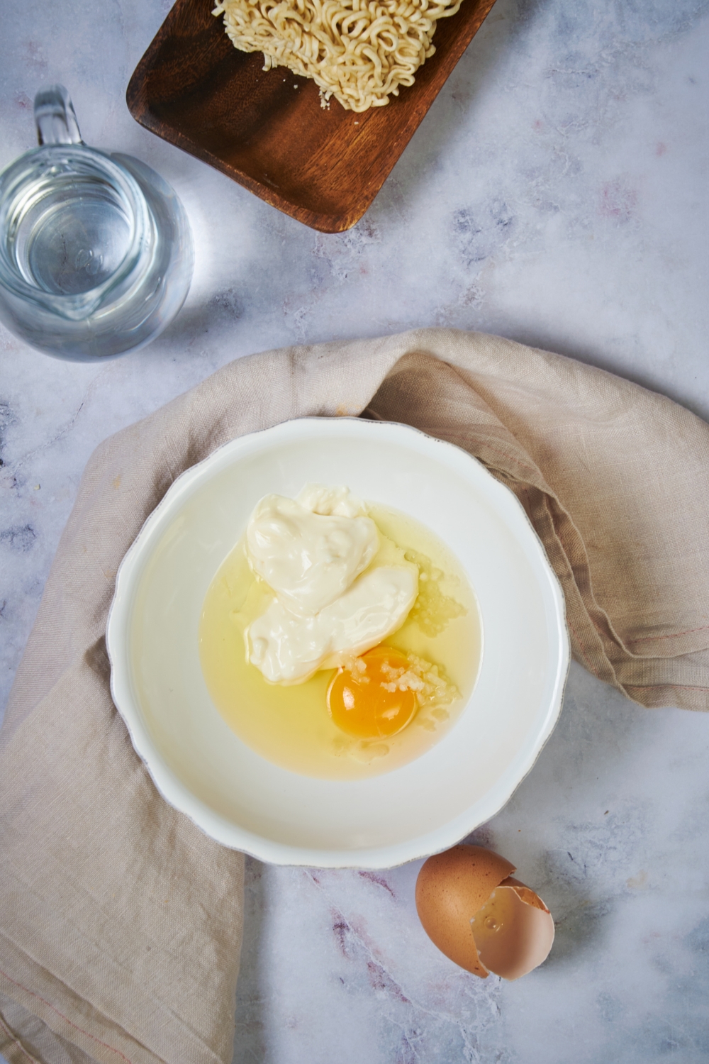 A white bowl with an egg and mayo in it.