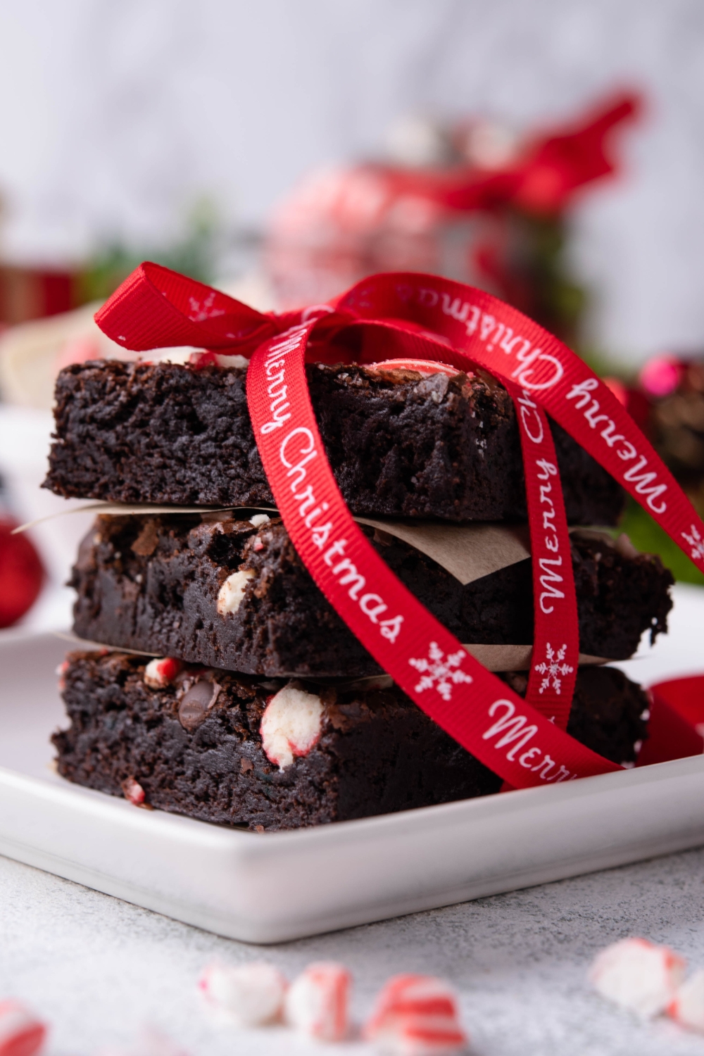 A plate with a stack of peppermint brownies tied with a merry Christmas bow.