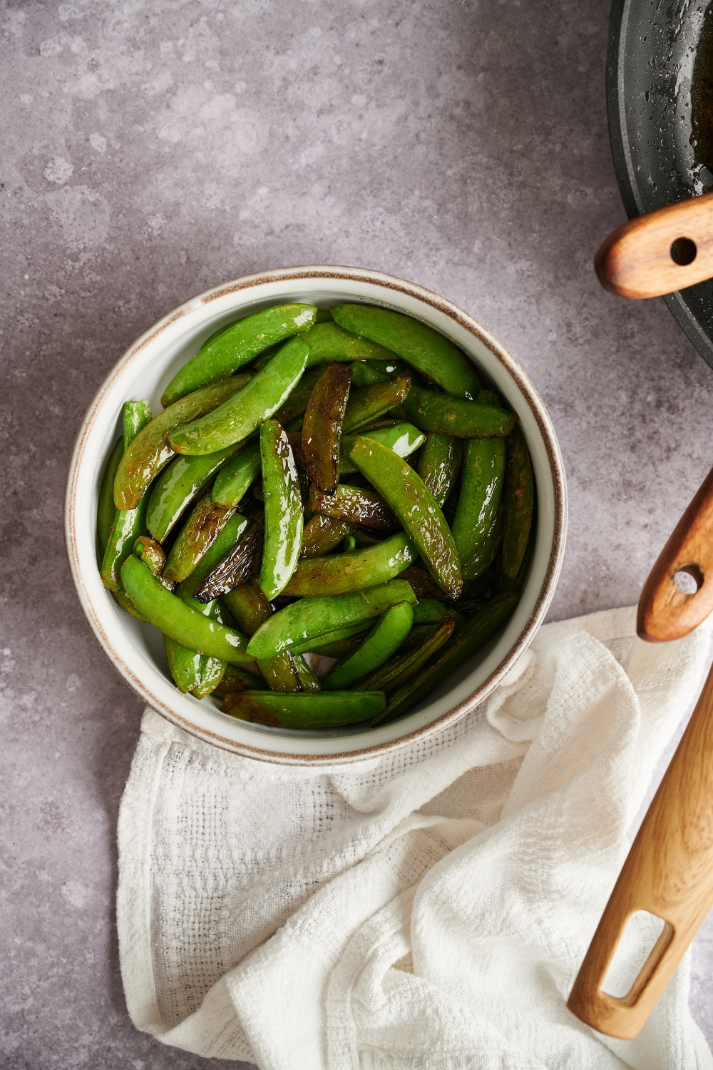 A small bowl with butter snap peas.