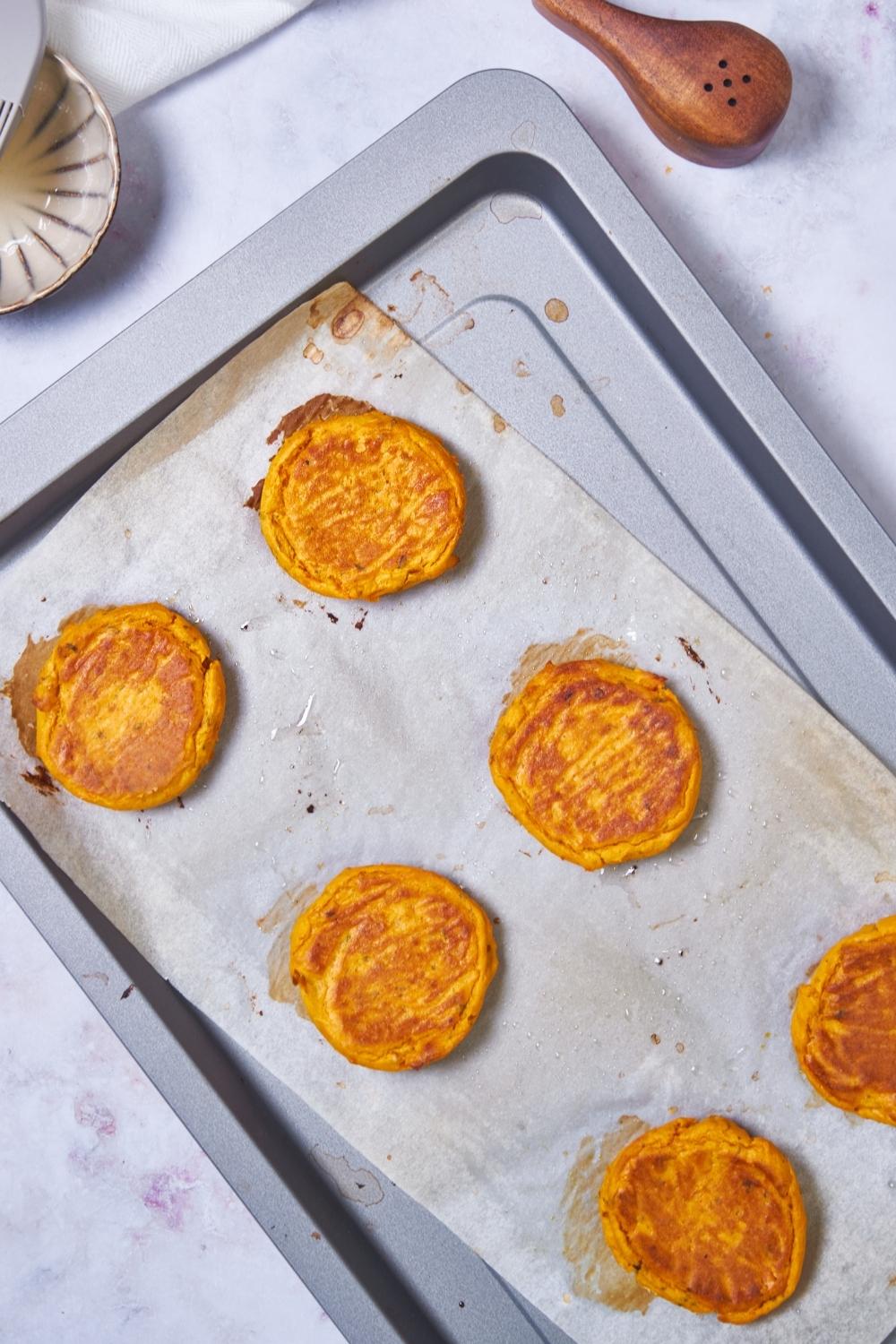 Sweet potato patties on a baking sheet lined with parchment paper.