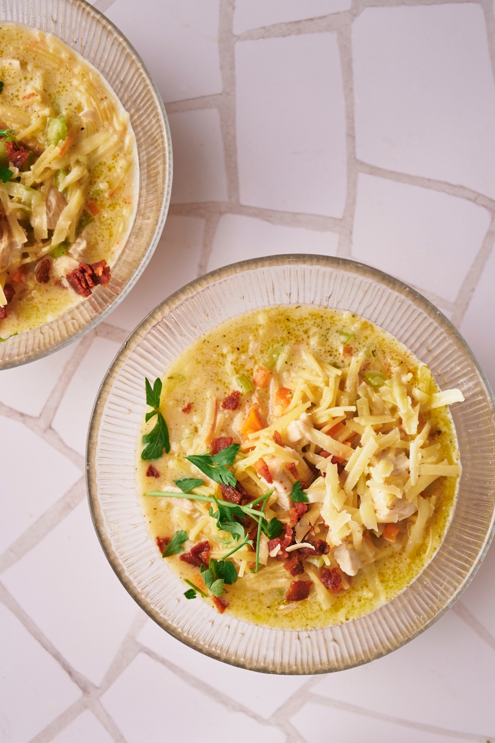 An overhead view of two bowls of crack chicken soup topped with bacon and cheese.