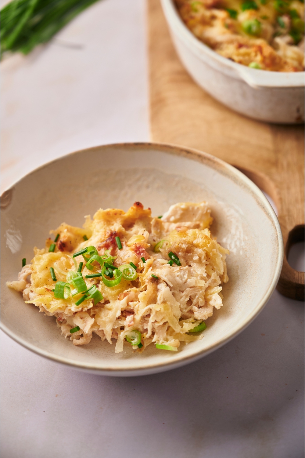 A white bowl with a serving of chicken hashbrown casserole.