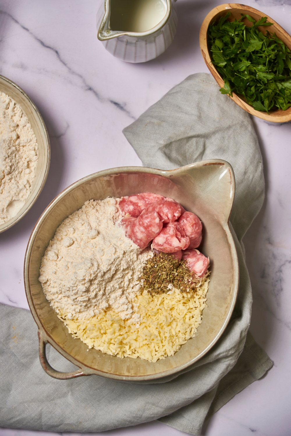 Mixing bowl filled with raw sausage, cheese, flour mixture, and seasoning.