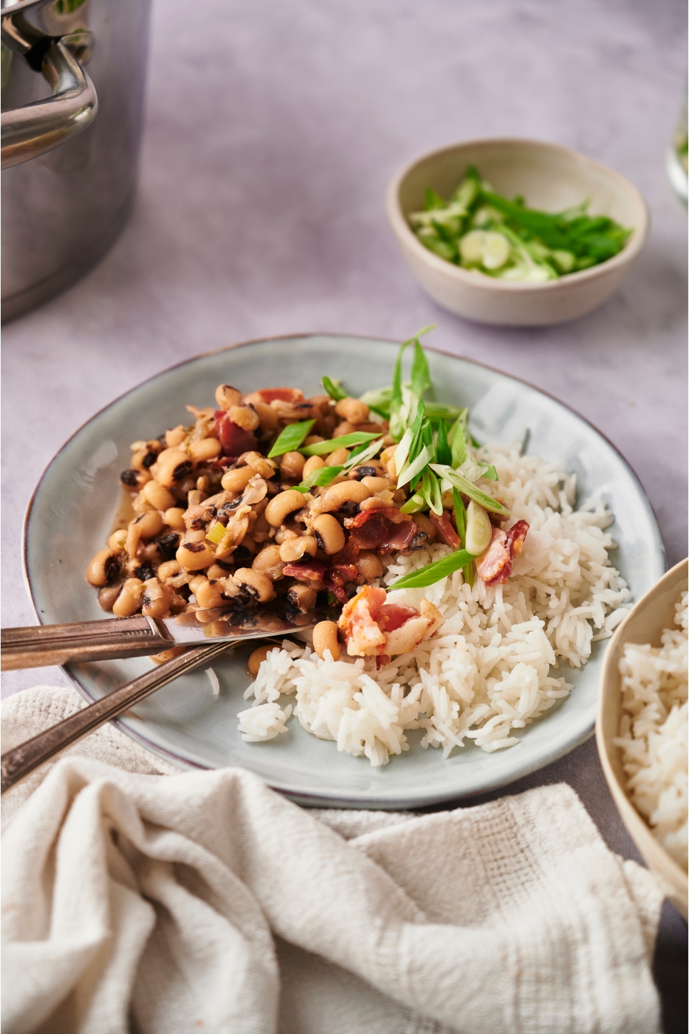 Blue bowl with hoppin' john, white rice, and a fork and knife.
