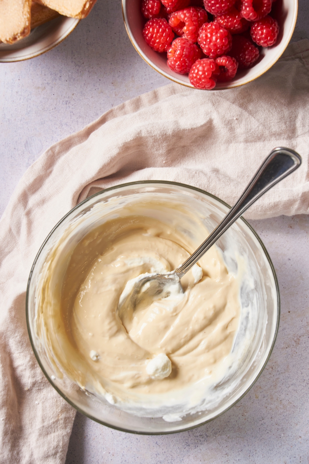 Clear mixing bowl with a spoon and a smooth cream cheese mixture.