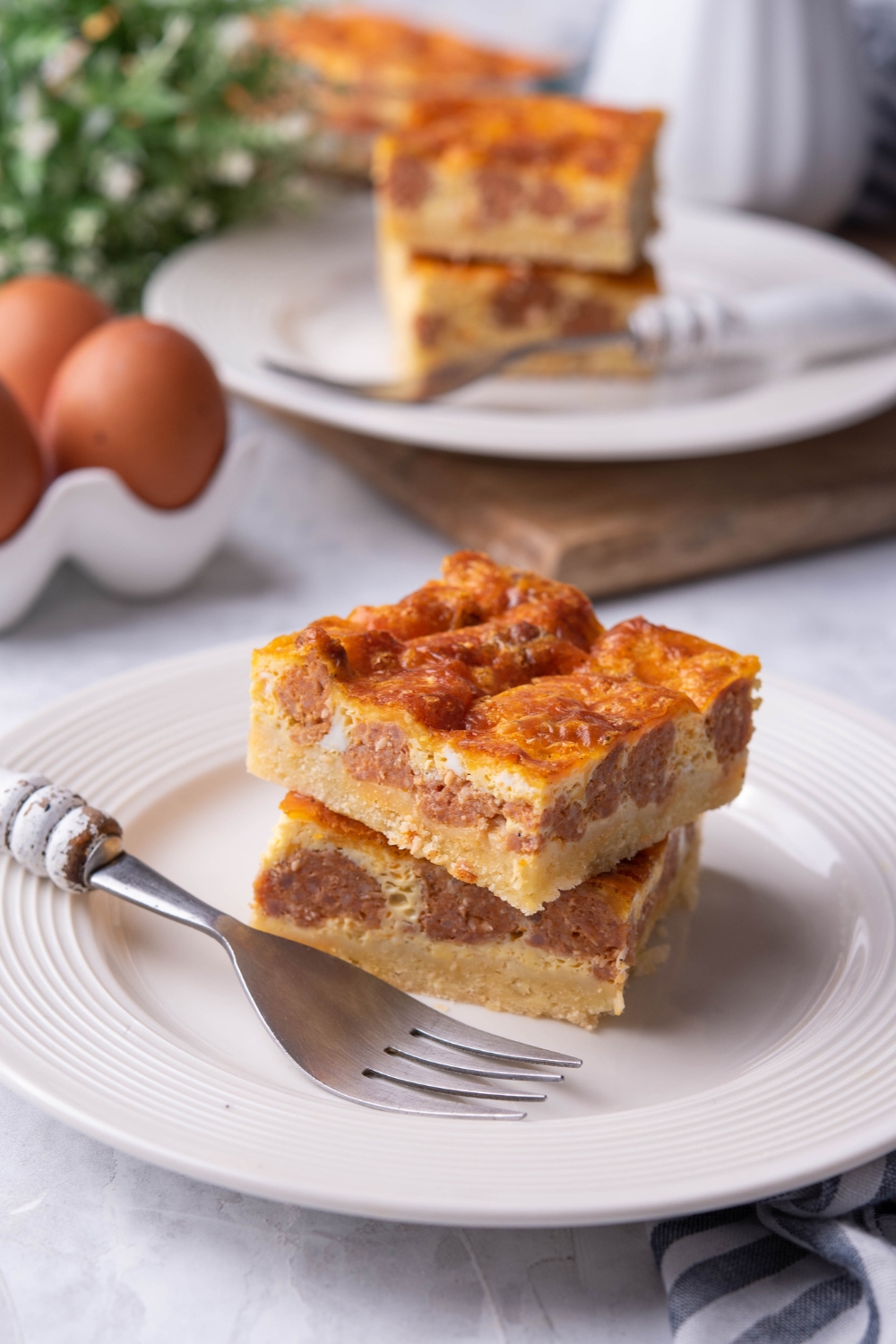 A plate with two squares of casserole and a fork laying next to them.