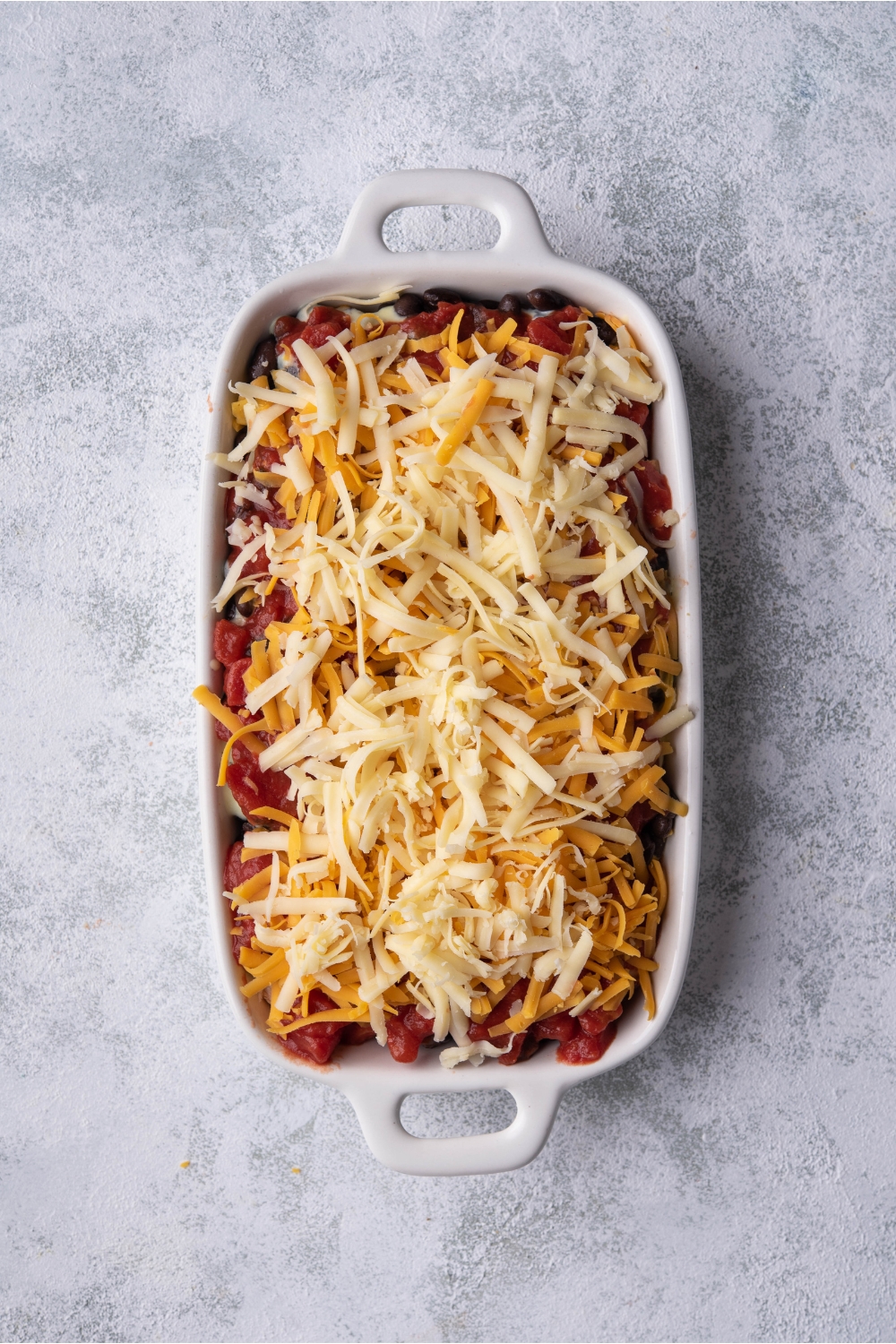 White baking dish with unbaked Mexican chicken casserole.