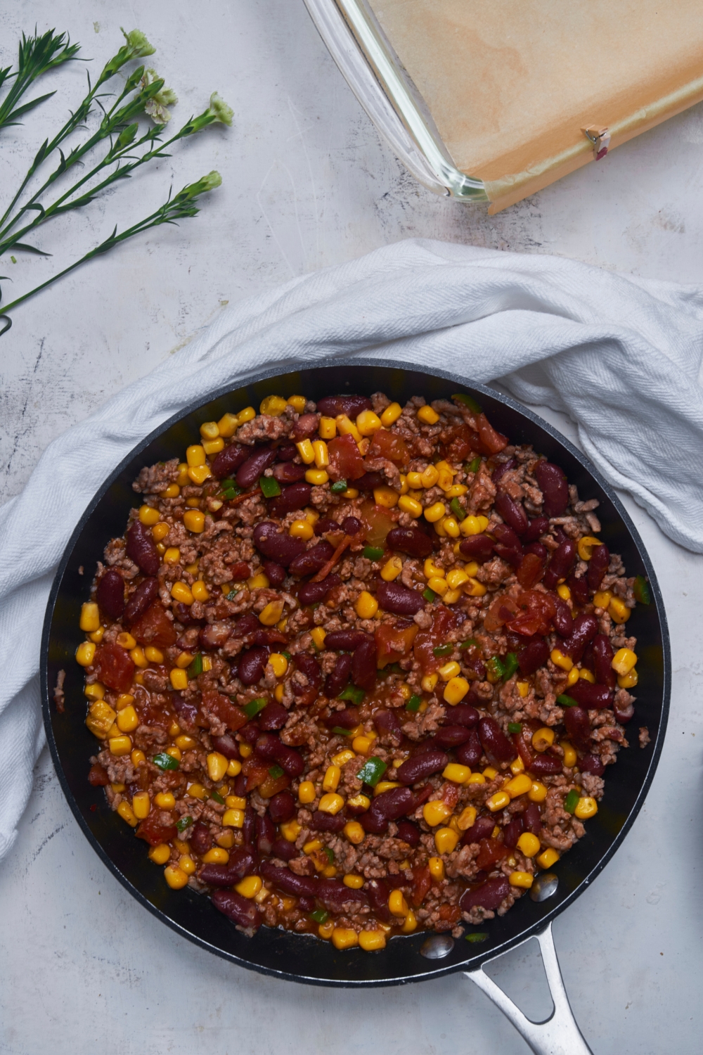 Black skillet filled with cooked ground beef mixed with beans, corn and salsa.