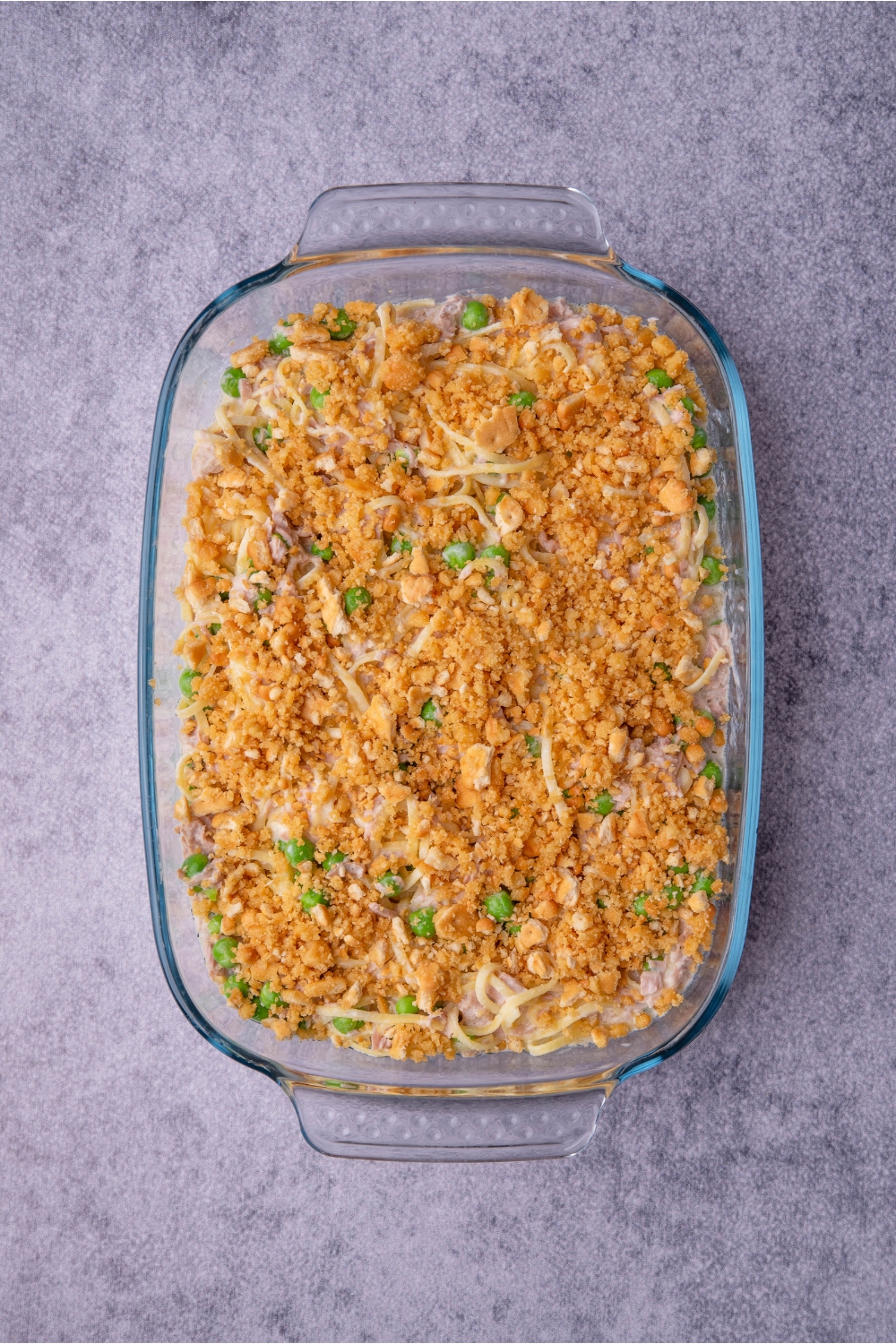 Clear baking dish with unbaked tuna noodle casserole topped with cracker crumb topping.