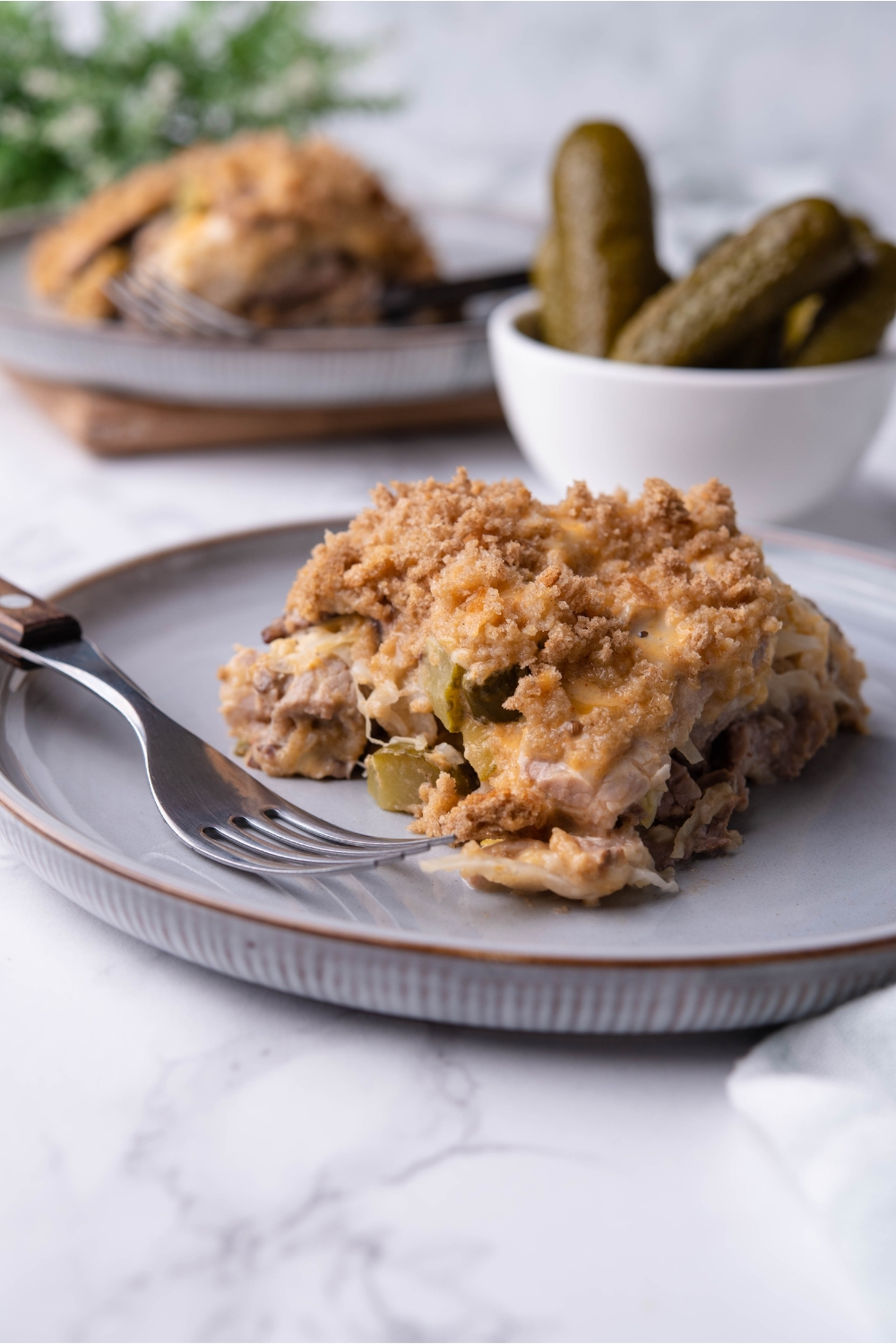 Serving of Reuben casserole on a blue plate with a fork on the plate and a second serving in the background.