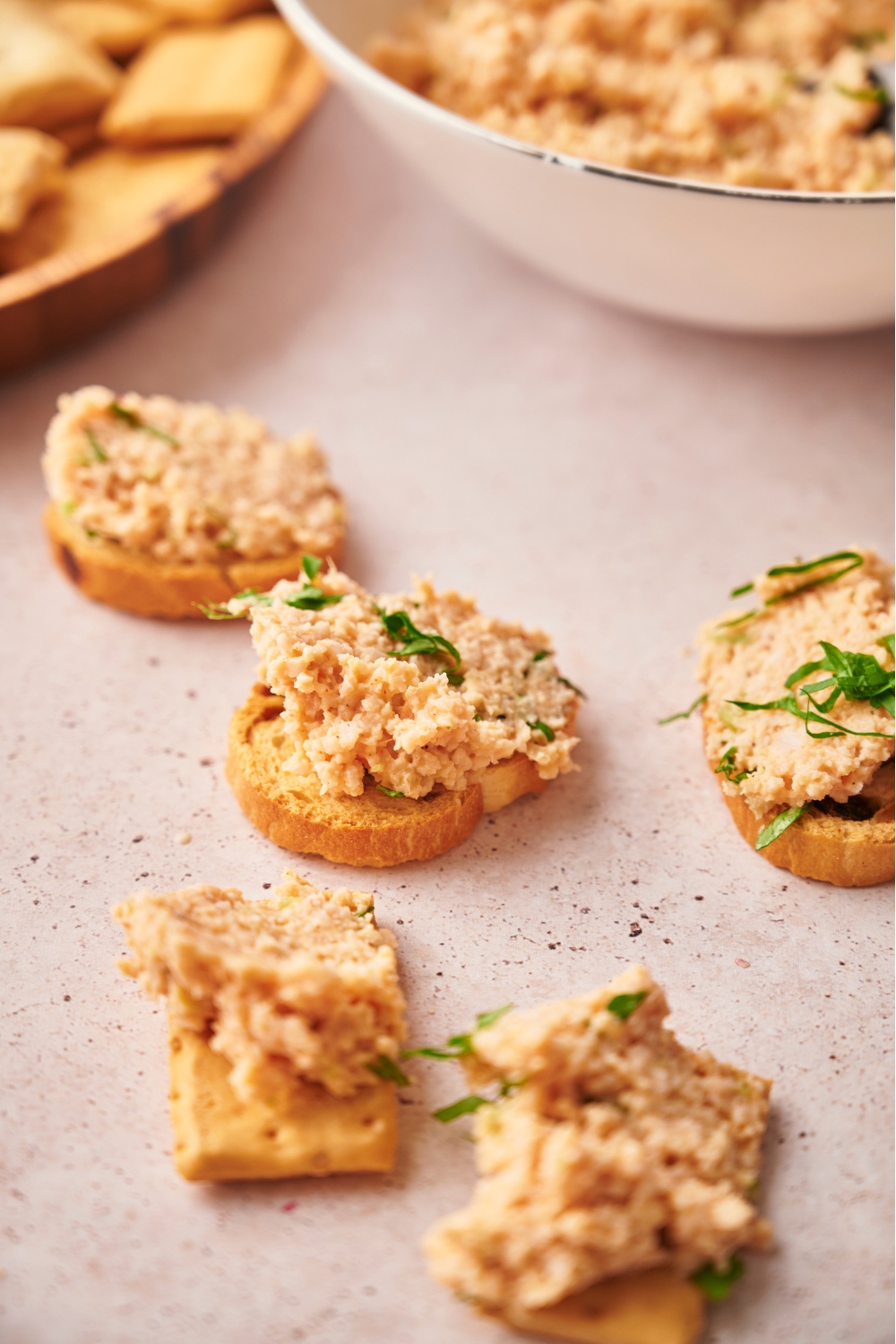 An assortment of bread and crackers topped with deviled ham and garnished with fresh herbs.