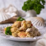 Seafood casserole garnished with parsley on a white plate.
