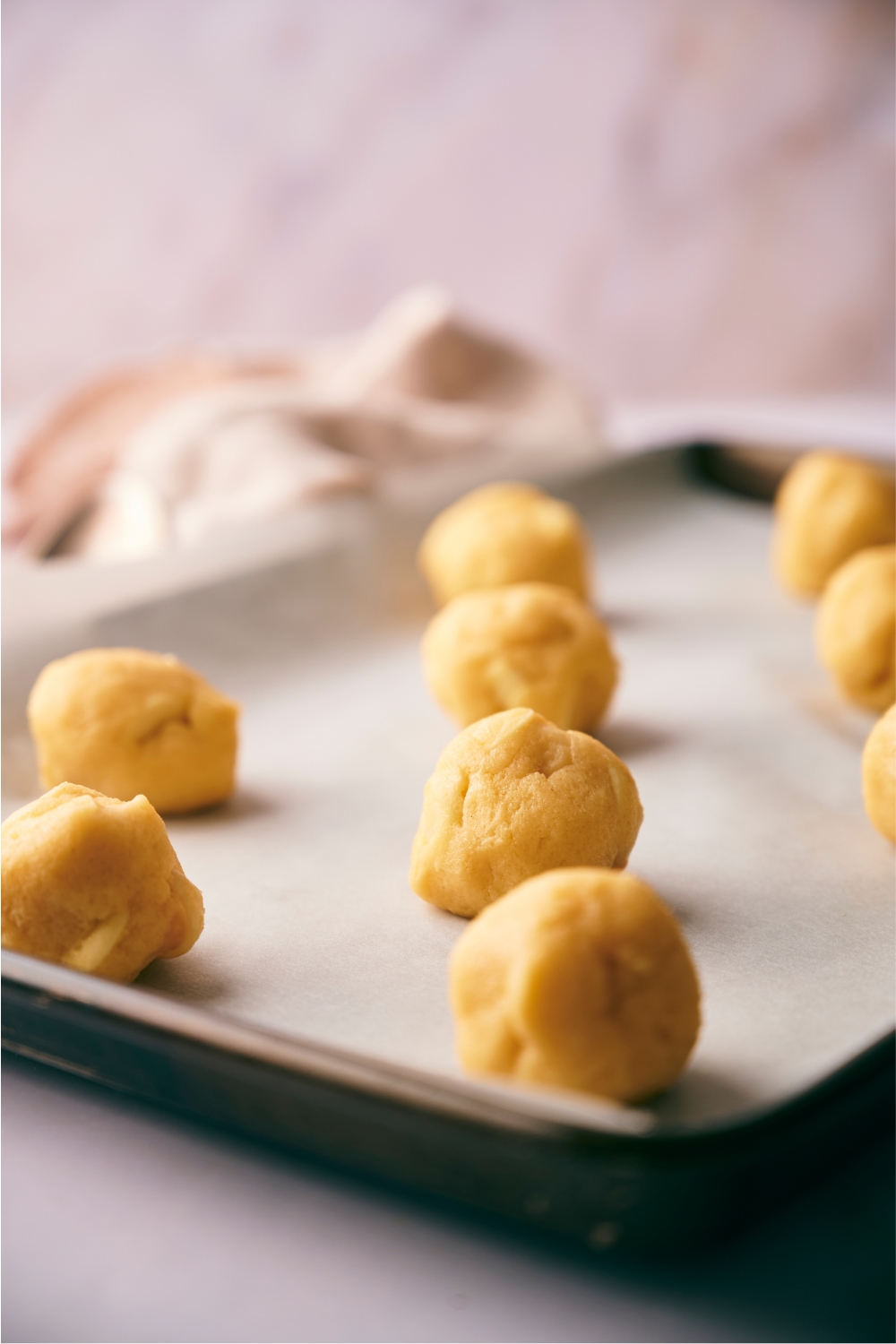 Baking sheet lined with parchment paper and cookie dough balls spread evenly on the baking sheet.