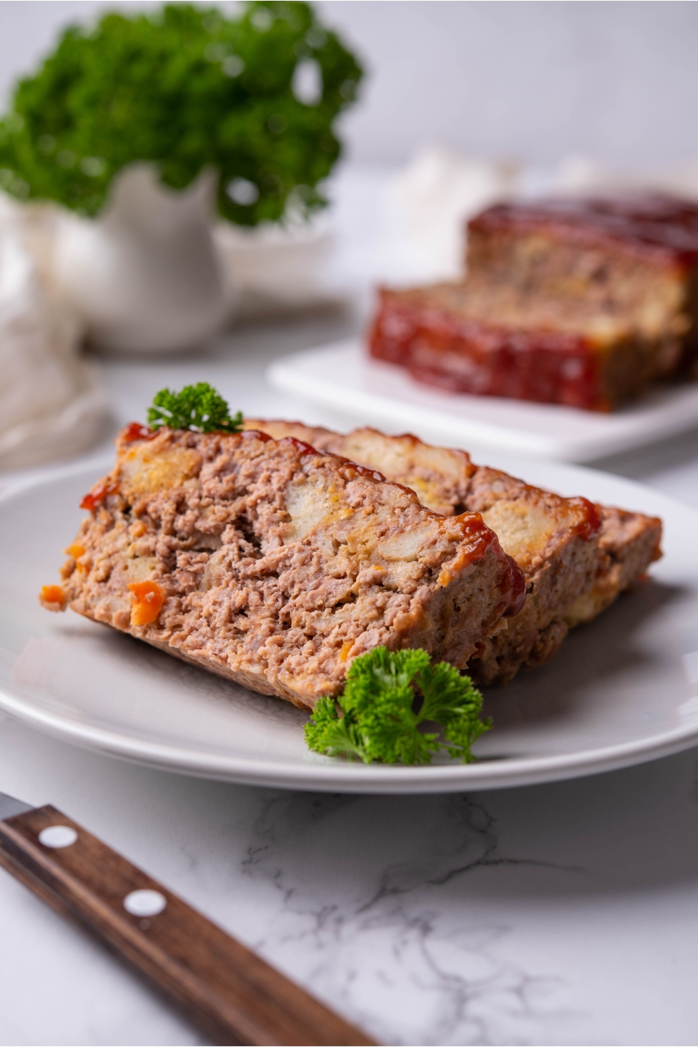 Three slices of stuffing meatloaf garnished with parsley on a white plate.