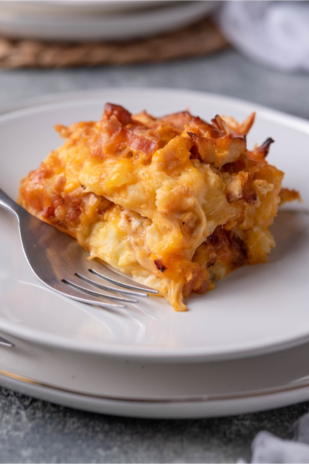 White plate with a serving of buffalo chicken casserole and a fork on the plate.