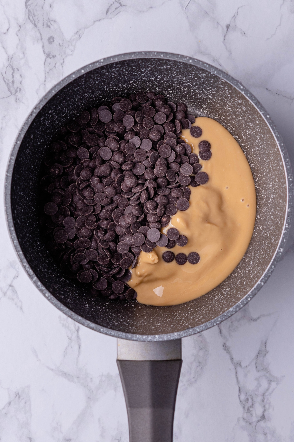 A sauce pot with peanut butter and chocolate chips in it.