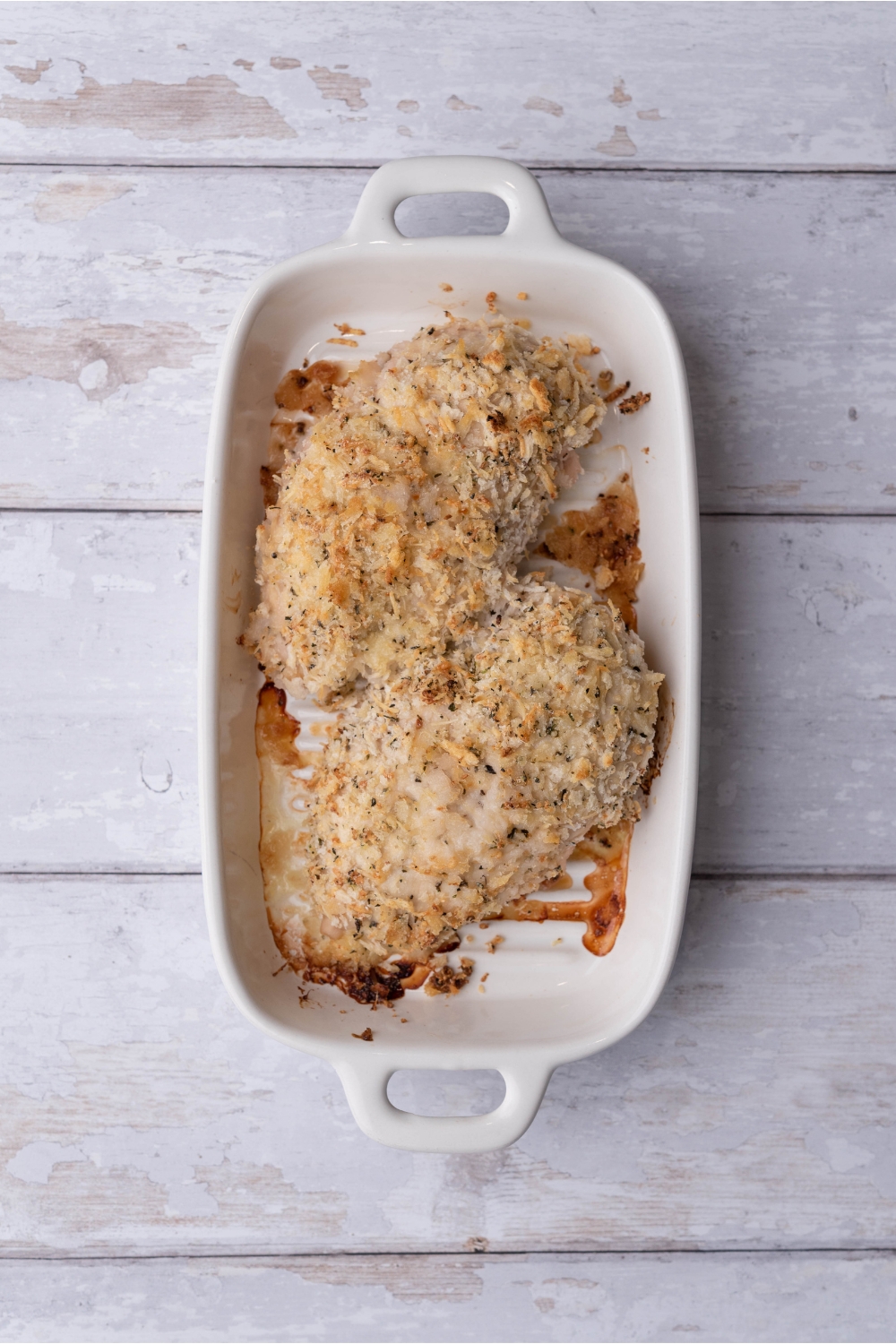 A white baking dish with two baked ranch chicken breasts.