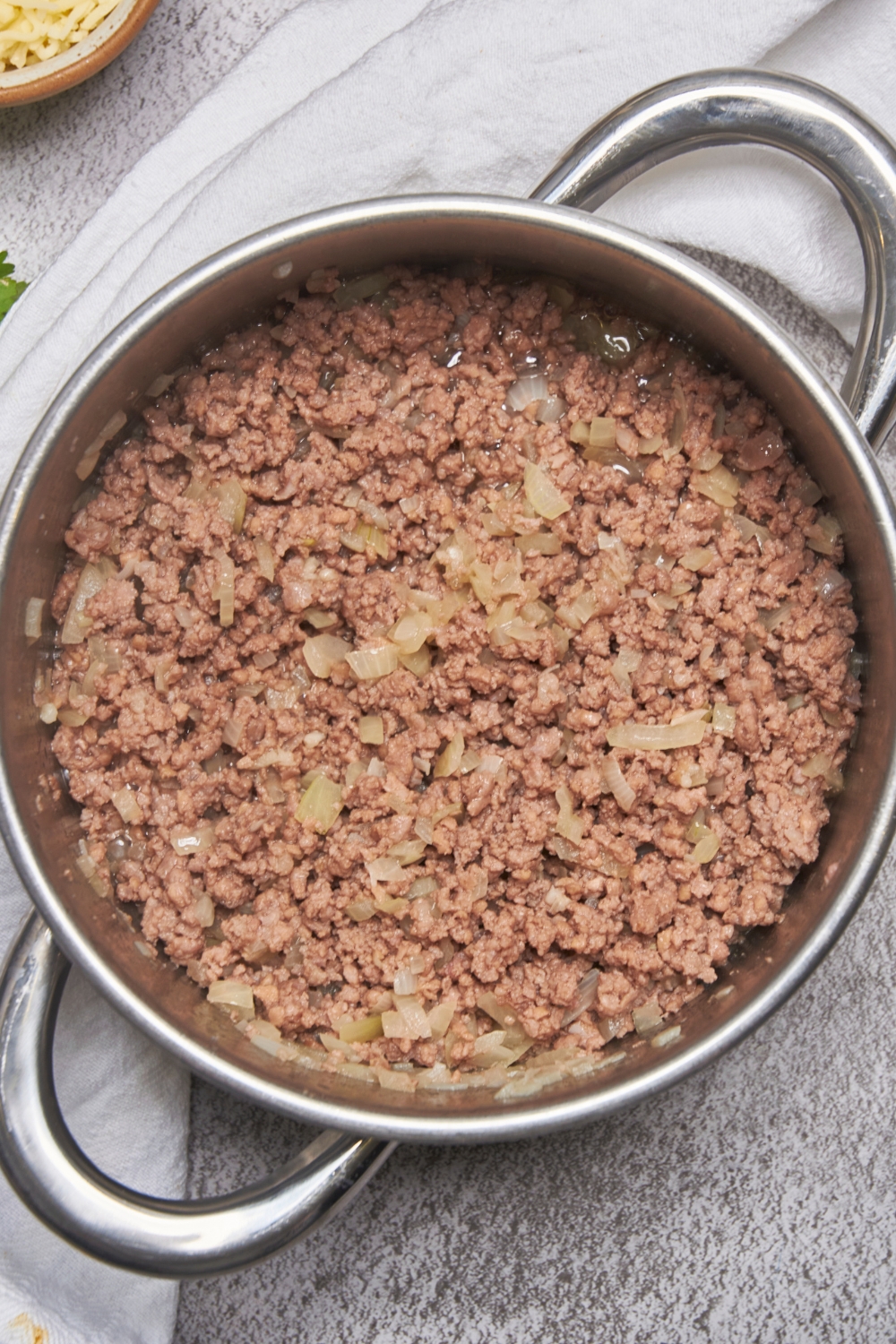 A deep pot of onions and ground beef cooking.