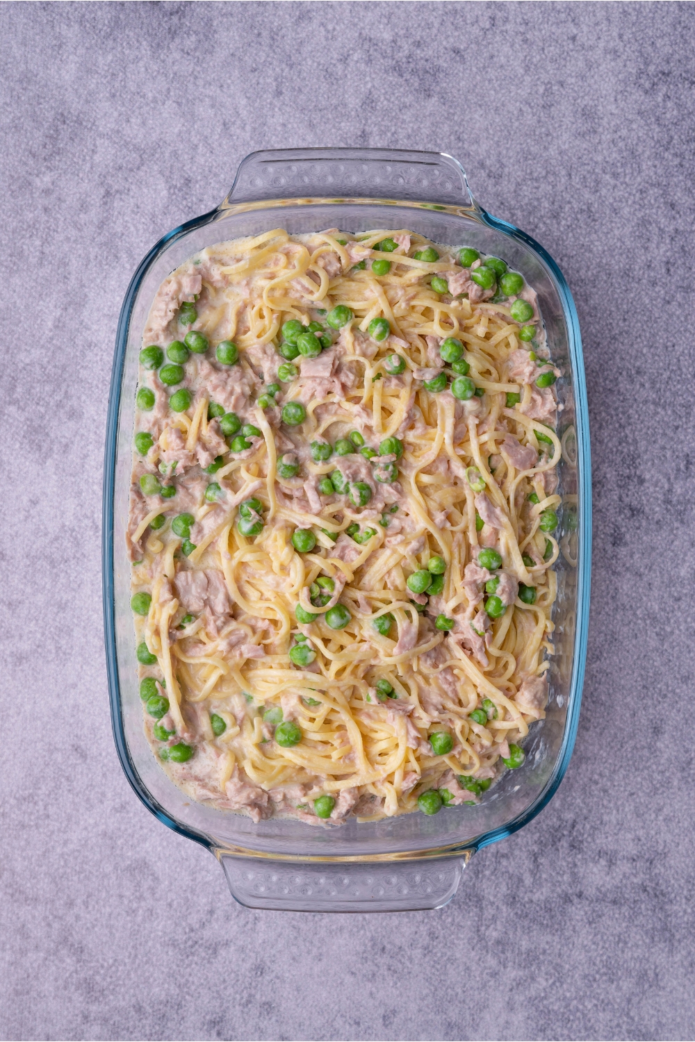 Clear baking dish with unbaked tuna noodle casserole.