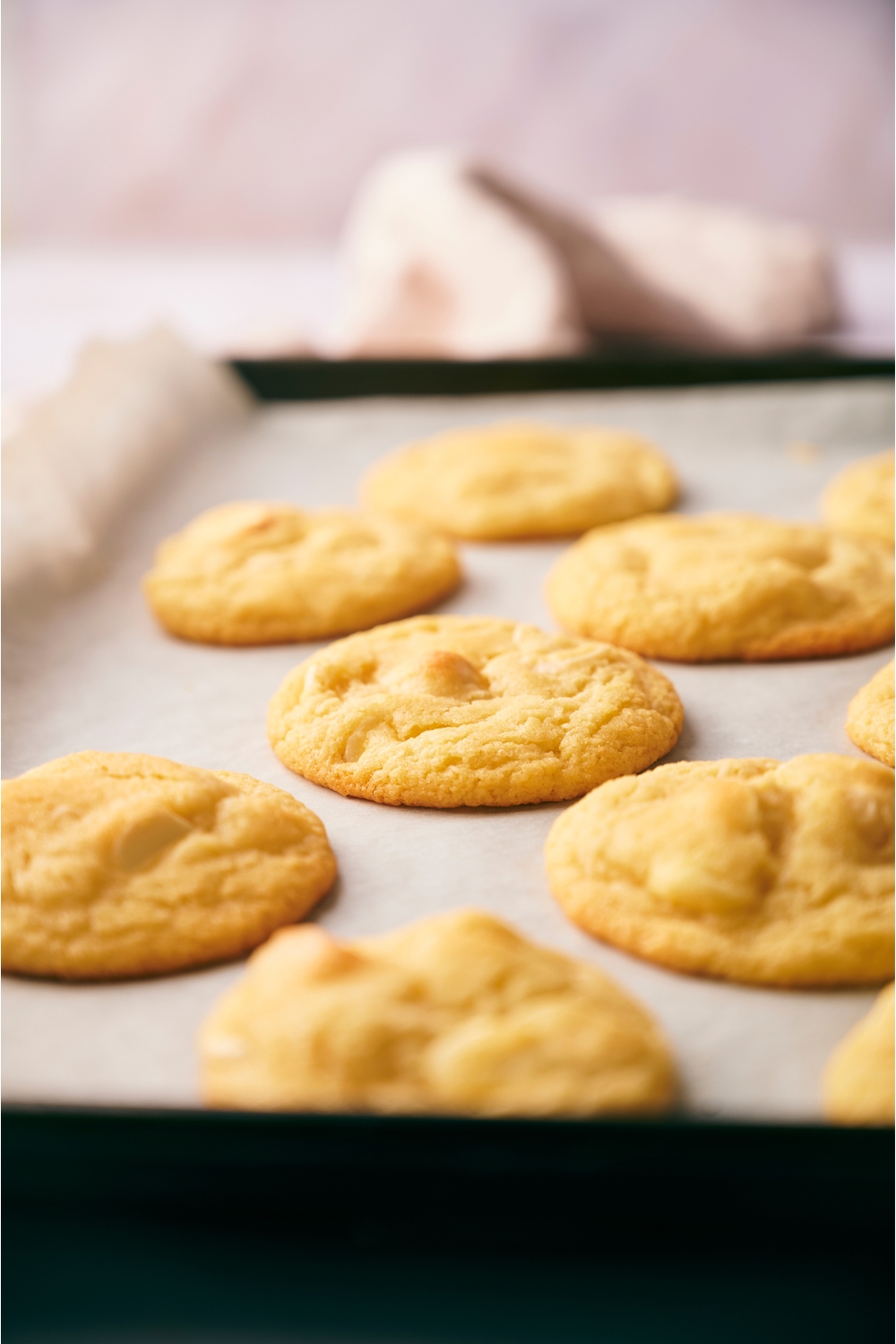 Baking sheet lined with parchment paper with freshly baked cookies spread evenly on the baking sheet.