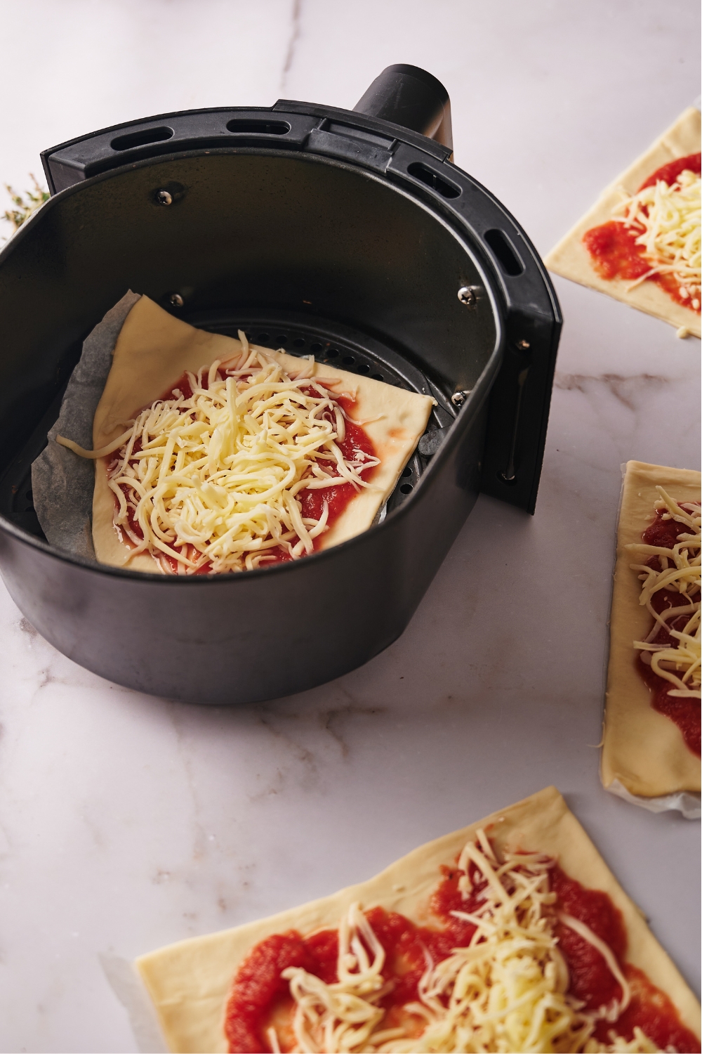 An air fryer basket with a slice of uncooked cheese pizza on it.