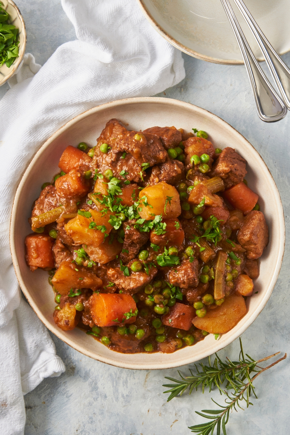Potatoes, carrots, peas and stew meat on a white plate.