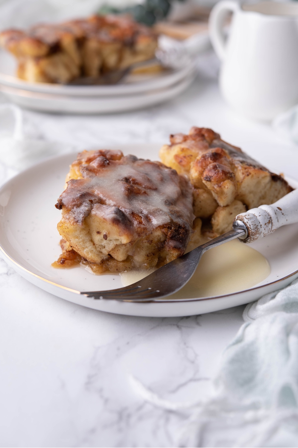Two cinnamon rolls on a white plate with icing on it.