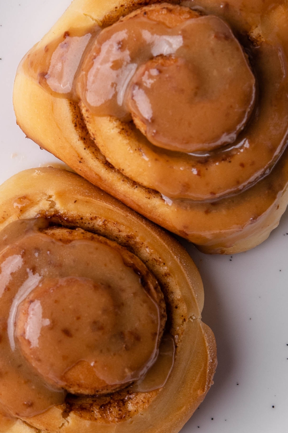 A close up of two cinnamon rolls on a plate.
