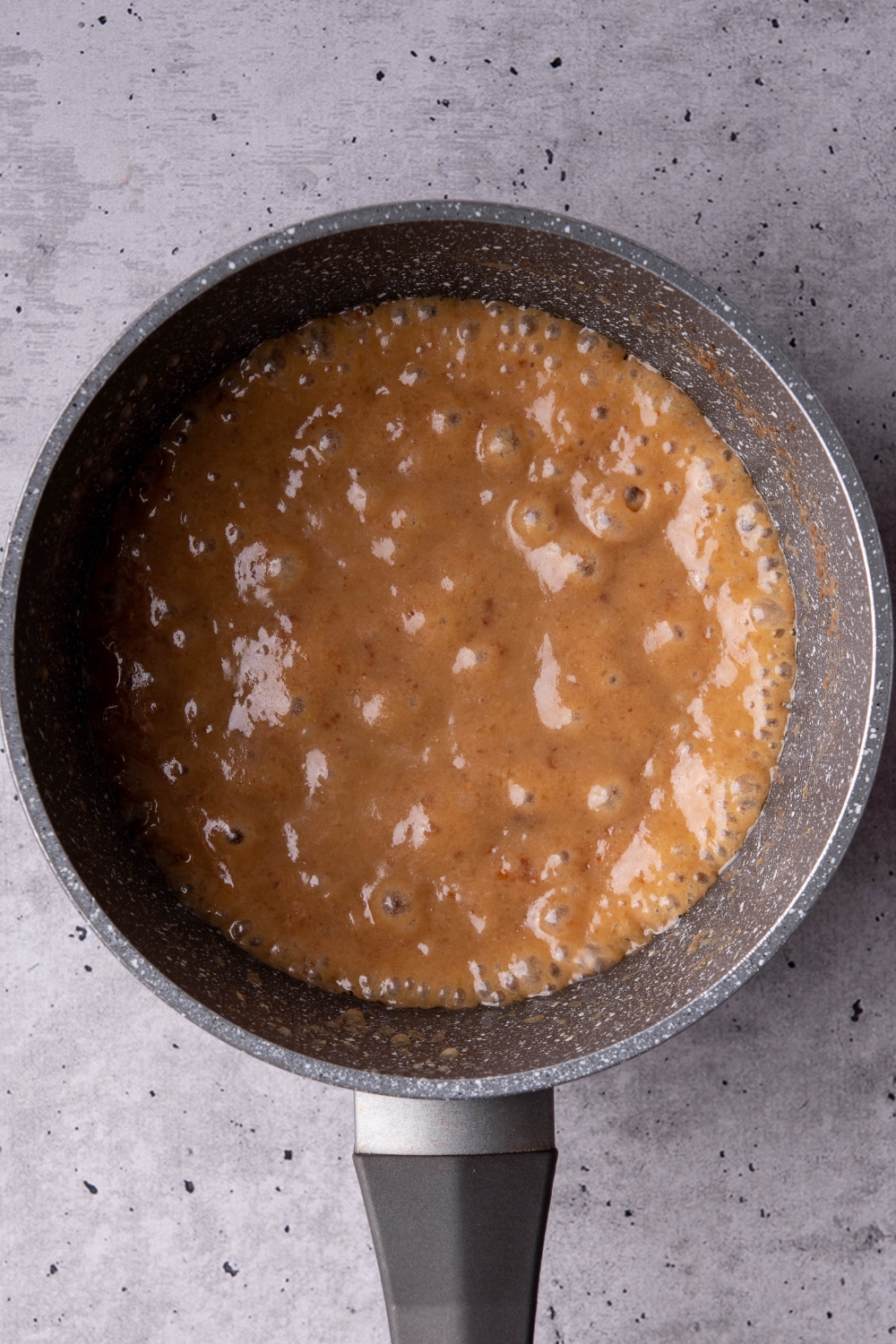 A saucepot with caramel being cooked.