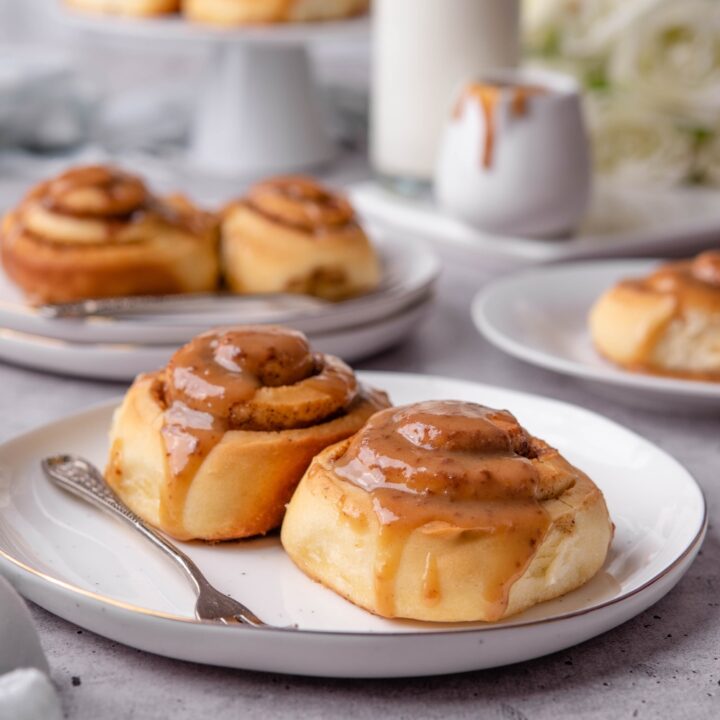 Two caramel cinnamon rolls on a white plate.