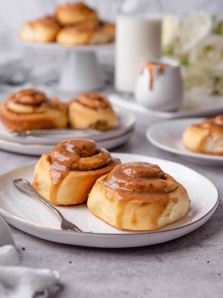 Two caramel cinnamon rolls on a white plate.