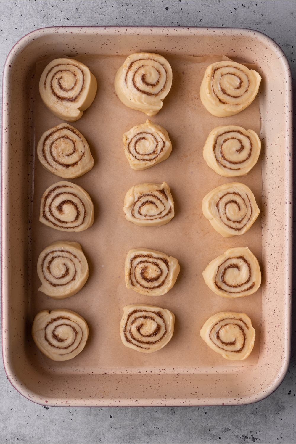 A baking pan with uncooked cinnamon rolls.