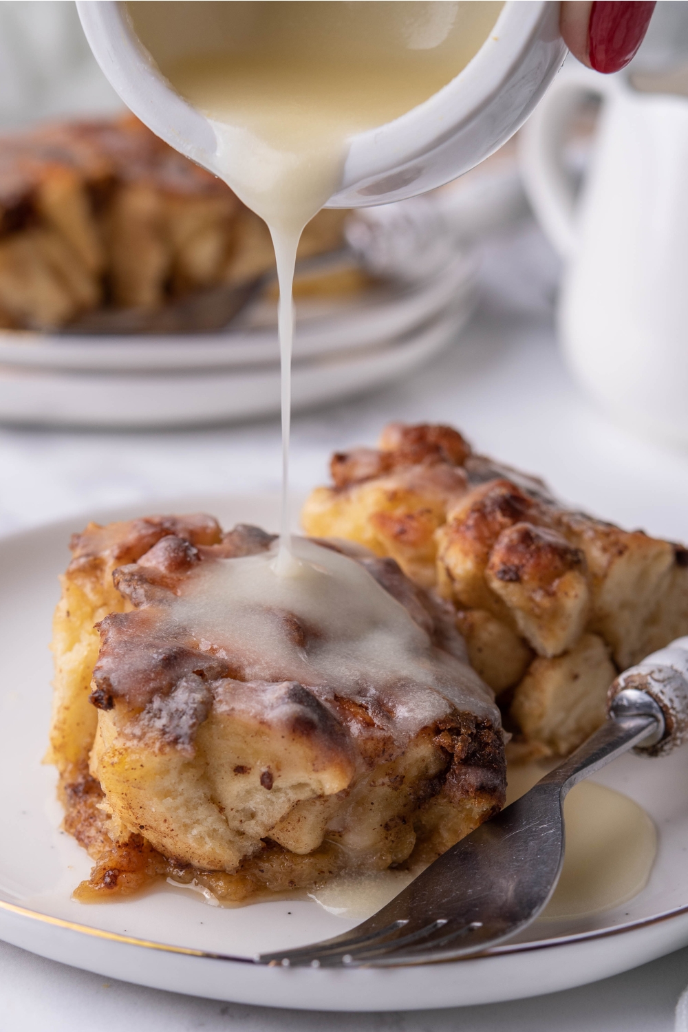 icing being drizzled on top of cinnamon rolls on a plate.