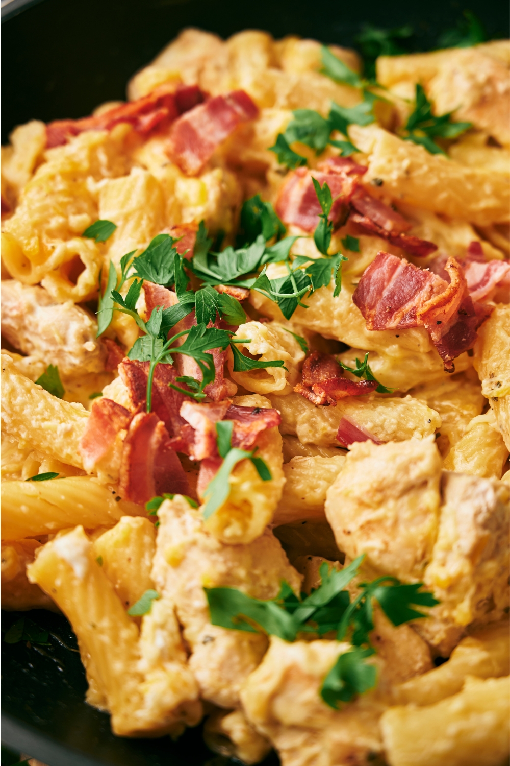 A close up of crack chicken pasta garnished with parsley and bacon..